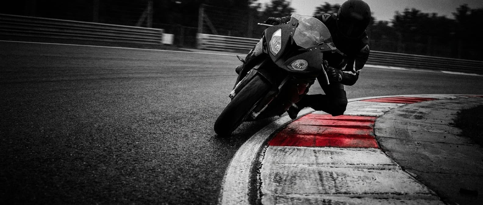 Motorrad in Schräglage kurz vor dem roten Kerb — die Ideallinie treffen